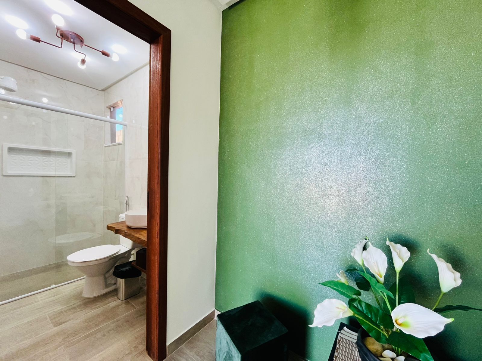Entrada de banheiro com detalhe verde e box ao fundo